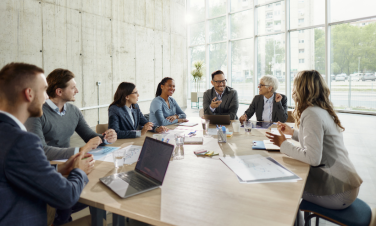 A meeting room with a diverse group of people sitting around a table.